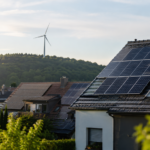 Hausdächer mit Solaranlagen und Windrad – nachhaltige Stromanbieter liefern grünen Strom